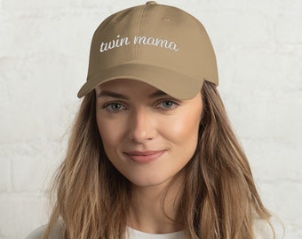 May include: A tan baseball cap with white embroidered text that reads "twin mama".