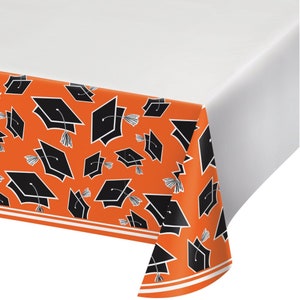May include: Orange plastic tablecloth with a black graduation cap pattern.