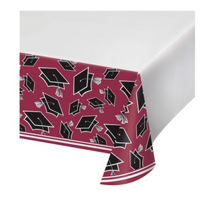 May include: Red plastic table cover with a black graduation cap pattern.