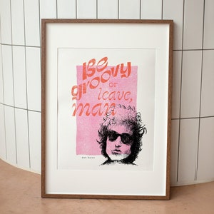 Bob Dylan be groovy or leave man quote framed in natural timber leaning on a tiled wall