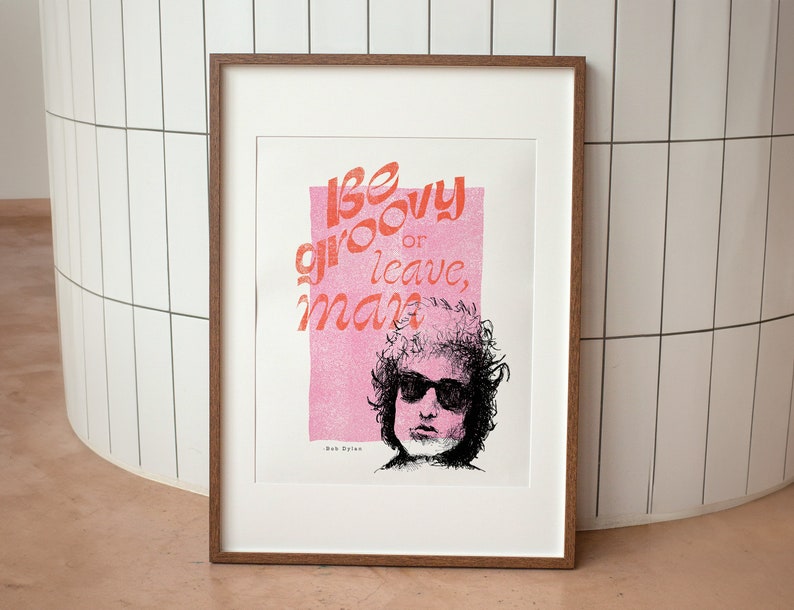 Bob Dylan be groovy or leave man quote framed in natural timber leaning on a tiled wall