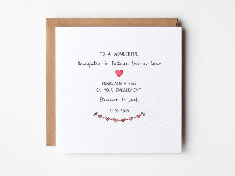 Puede incluir: Una tarjeta blanca con un sobre marr&oacute;n. La tarjeta tiene un mensaje escrito a mano que dice "To a wonderful Daughter & Future Son-in-law Congratulations on your engagement Eleanor & Jack 29.02.2024". Hay peque&ntilde;os corazones rojos dibujados en la parte inferior de la tarjeta.