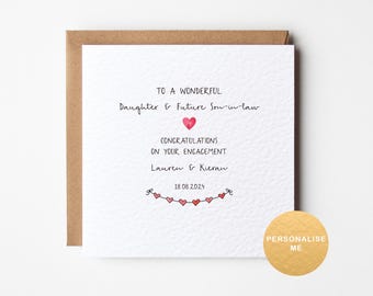 May include: A white card with a brown border, featuring a message that reads "To a wonderful Daughter & Future Son-in-law Congratulations on your engagement Lauren & Kieran 18.08.2024". The message is written in black ink and is surrounded by a string of red hearts.
