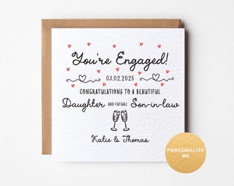 May include: A white card with black text and red hearts that reads "You're Engaged! 03.02.2025 Congratulations to a beautiful Daughter and future Son-in-law Katie & Thomas".