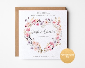 May include: A wedding card with a floral heart design. The card features the names "Josh & Charlie" and the date "14th May 2025". The text "To a special son & daughter-in-law" and "On your wedding day" are also included. A gold sticker says "Personalise Me".
