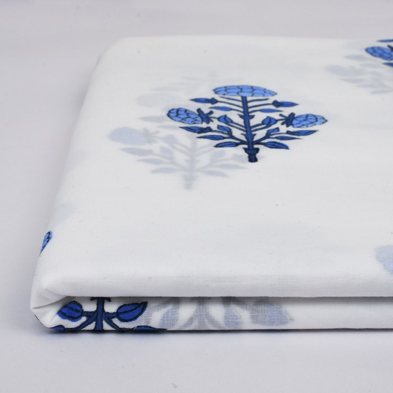 Puede incluir: Tela blanca con estampado floral azul. La tela est&aacute; doblada por la mitad y el estampado es visible en ambos lados.