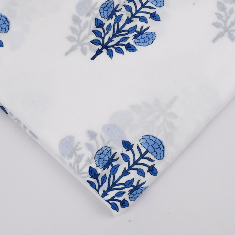 Puede incluir: Tela blanca con estampado floral azul. La tela presenta un patr&oacute;n repetitivo de flores y hojas azules sobre un fondo blanco.