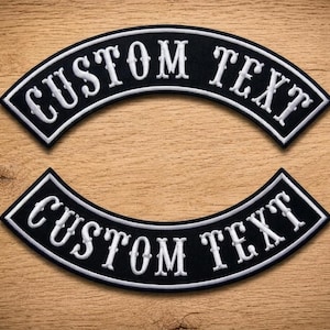 Op de afbeelding: Twee gebogen, zwarte geborduurde patches met witte randen en wit gestikte tekst die CUSTOM TEXT leest. De patches hebben een gebogen ontwerp met een strak, vet lettertype en een contrastrijke uitstraling die geschikt is voor toepassing.