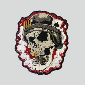 May include: Embroidered patch featuring a skull wearing a military helmet with a playing card tucked in the side. The skull is smoking a cigarette and has gold teeth. The patch is surrounded by red and white smoke.