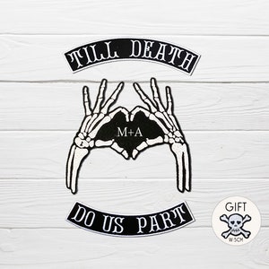 Puede incluir: Parches termoadhesivos en blanco y negro con el texto "Till Death Do Us Part" y una forma de corazón de mano de esqueleto con las iniciales "M+A".