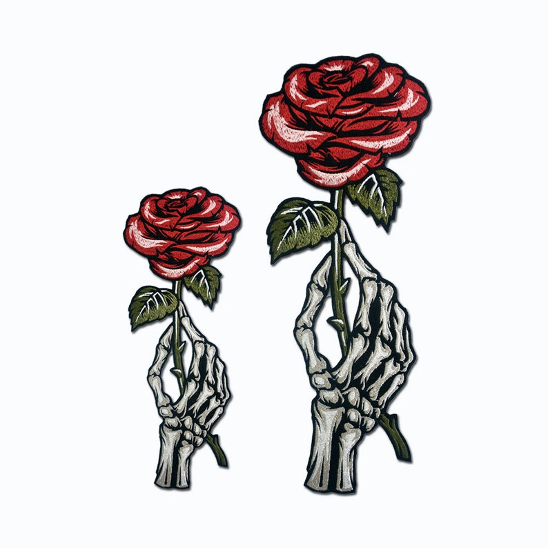May include: Two embroidered iron-on patches featuring a skeleton hand holding a red rose. The larger patch has a larger rose and a more detailed skeleton hand.