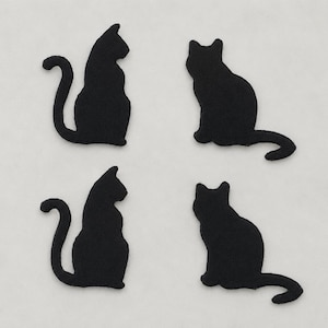 Peut inclure: Quatre écussons en forme de chat noir disposés en grille. Deux écussons représentent un chat assis droit avec une queue courbée, tandis que les deux autres montrent un chat assis dans une posture légèrement différente avec la queue étendue.