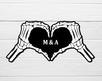May include: Two skeleton hands forming a heart shape with the initials "M & A" inside.