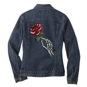 May include: A dark blue denim jacket with a red rose and a skeleton hand holding the stem of the rose embroidered on the back.