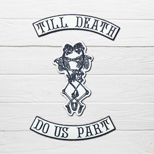 May include: Two skeleton figures embracing, with the text "Till Death Do Us Part" in a black and white arched banner design.