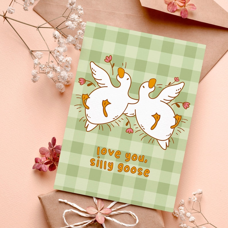 printable silly goose card. soft gingham background with two geese lying on their backs surrounded by flowers. text reads love you silly goose. Printable anniversary card for boyfriend or girlfriend