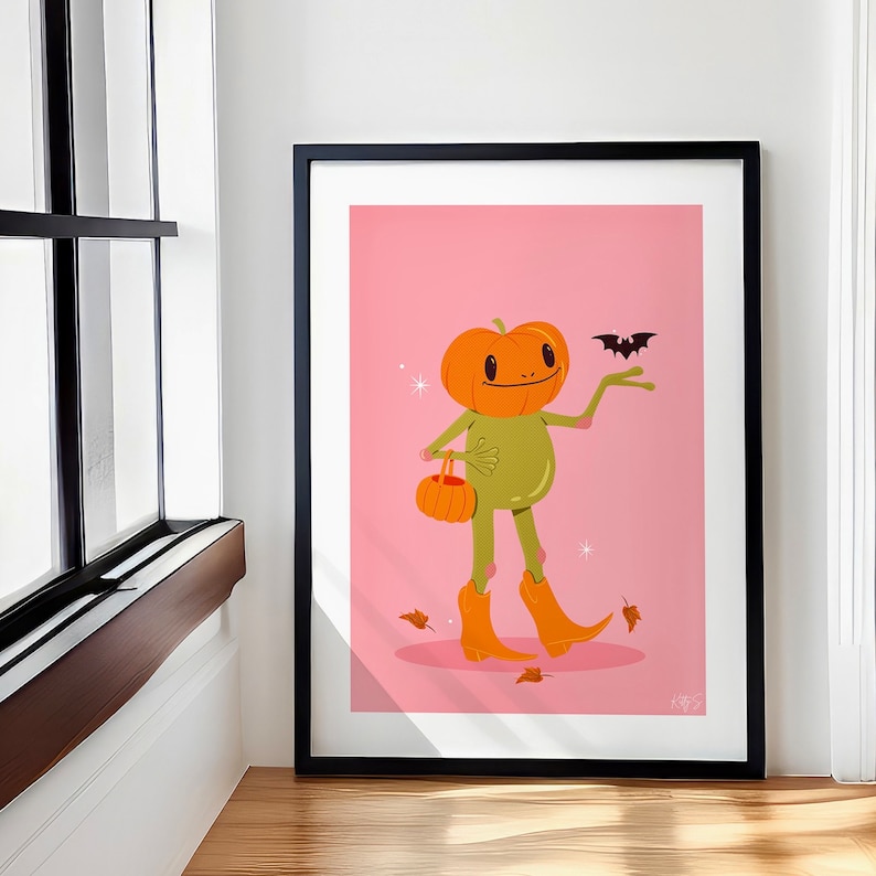 howdy halloween frog art print in pink, green and orange. UPS style cartoon illustration of a frog with a pumpkin head wearing orange cowboy boots and carrying a pumpkin bag. next to him flies a little bat, leaves surround his feet