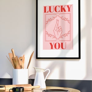 minimal kitchen with wooden dining table and kitchen utensils. On the wall is a large from with retro pink and red art print