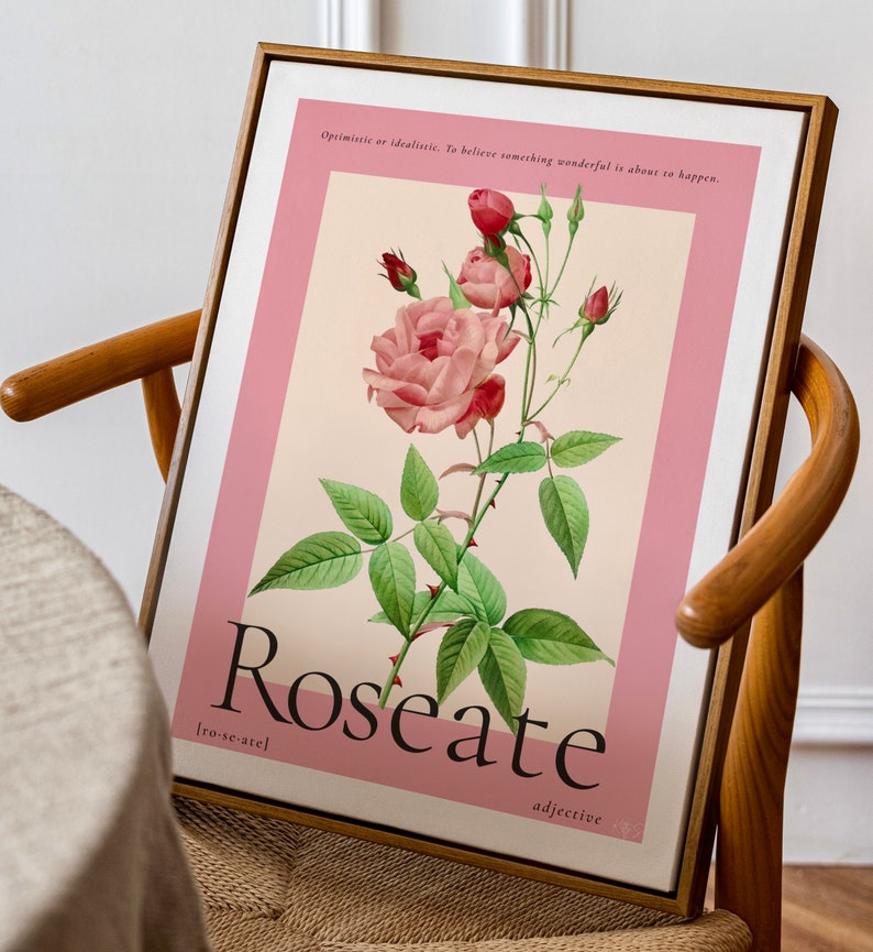 floral art print in pink featuring a large budding rose sits in a wooden frame on a mid-century chair in a dining room