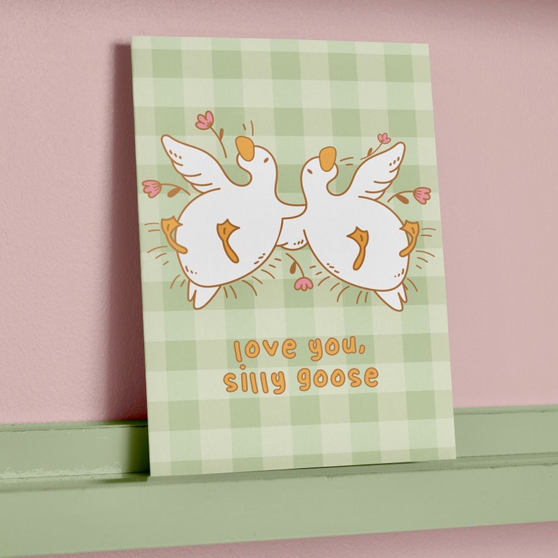 printable silly goose card. soft gingham background with two geese lying on their backs surrounded by flowers. text reads love you silly goose. Printable anniversary card for boyfriend or girlfriend