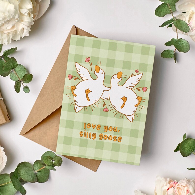 printable silly goose card. soft gingham background with two geese lying on their backs surrounded by flowers. text reads love you silly goose. Printable anniversary card for boyfriend or girlfriend