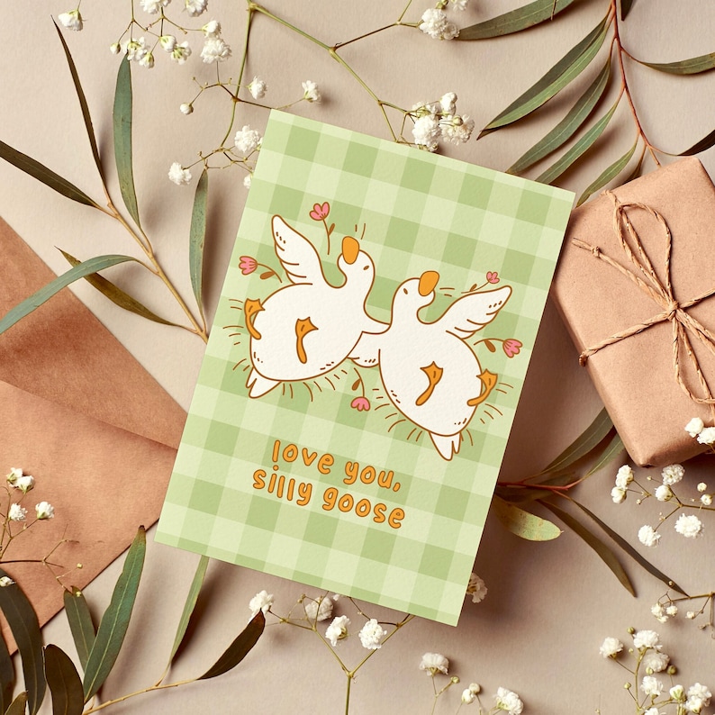 printable silly goose card. soft gingham background with two geese lying on their backs surrounded by flowers. text reads love you silly goose. Printable anniversary card for boyfriend or girlfriend