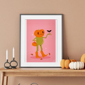 halloween frog art print in pink, green and orange surrounded by pumpkins. UPS style cartoon illustration of a frog with a pumpkin head wearing orange cowboy boots and carrying a pumpkin bag. next to him flies a little bat, leaves surround his feet