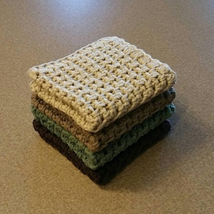 May include: A stack of four crocheted dishcloths in various shades of green, brown, and beige. The dishcloths are made with a simple stitch pattern and are perfect for cleaning and drying dishes.