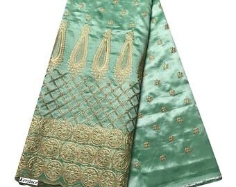 Puede incluir: Tela de satén verde con bordado dorado con motivos de paisley y circulares. La tela está doblada por la mitad, mostrando ambos lados.