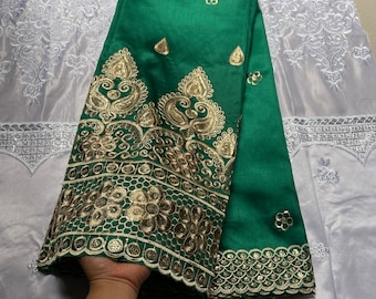 Puede incluir: Tela verde con bordado dorado. La tela tiene un diseño de paisley y un borde festoneado.