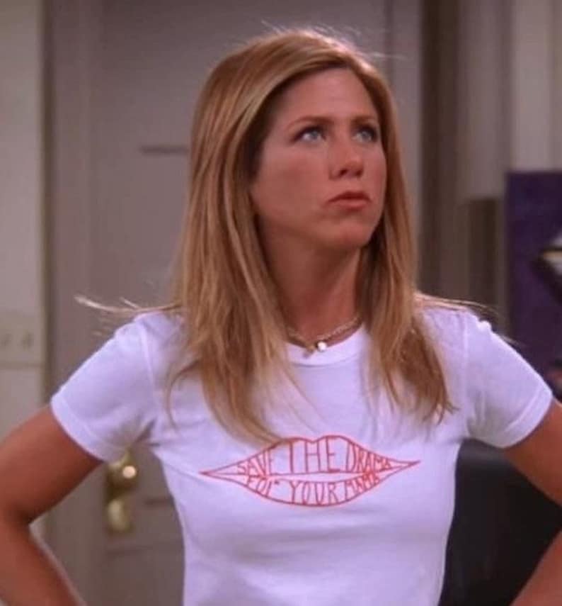 May include: A white t-shirt featuring a red lip design with the words "SAVE THE DRAMA FOR YOUR MAMA". The shirt has short sleeves and is worn by a person with blonde hair.