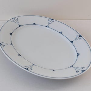 May include: A white oval ceramic plate with a blue floral design around the edge.