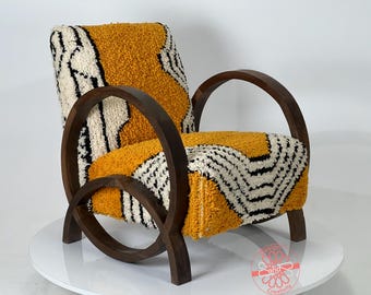 Puede incluir: Un sillón amarillo y blanco con estampado y un marco de madera circular único. El sillón está tapizado con una tela suave y texturizada.