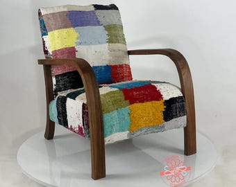 Puede incluir: Un sillón de madera con un asiento y respaldo de tela patchwork. La tela está compuesta por cuadrados de diferentes colores, incluyendo rojo, azul, amarillo, verde y blanco.