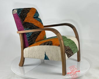 Puede incluir: Un sillón colorido con tapicería de tela con estampado geométrico. La silla tiene un marco de madera con brazos y patas curvos.