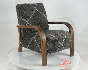 May include: A brown wooden armchair with curved arms and a gray and white patterned fabric upholstery.