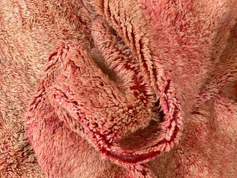 Op de afbeelding: Close-up van een zachte, roze en rode, pluche stof met een textuur, geweven patroon.