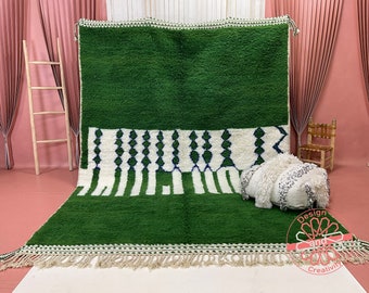 May include: A green and white Moroccan rug with a geometric pattern. The rug has a fringe border and is made of wool.