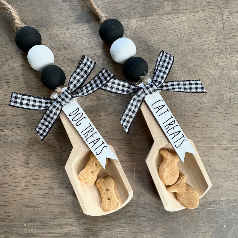 May include: Two wooden scoops with black and white checkered ribbon and beads. One scoop says "Dog Treats" and holds dog biscuits. The other scoop says "Cat Treats" and holds cat treats.