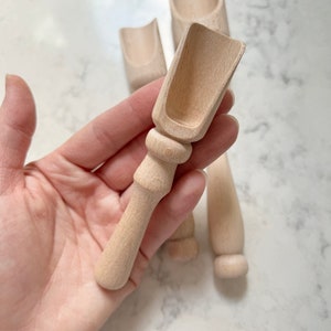 May include: Three wooden scoops with a rounded handle and a shallow bowl. The scoops are made of light wood and have a natural finish.