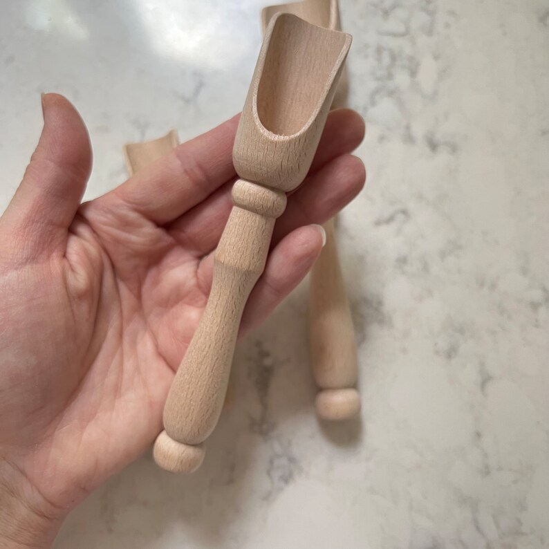 May include: Two wooden scoops with a rounded handle. The scoops are made of light brown wood and have a smooth finish.