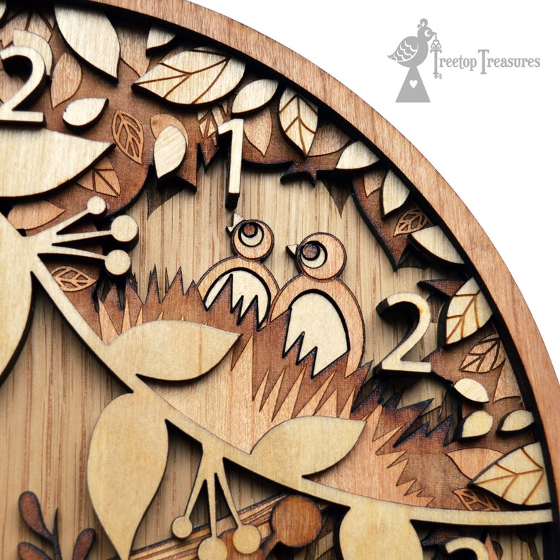 May include: A wooden clock face with a detailed design of birds, leaves, and berries. The numbers 1 and 2 are visible on the clock face.