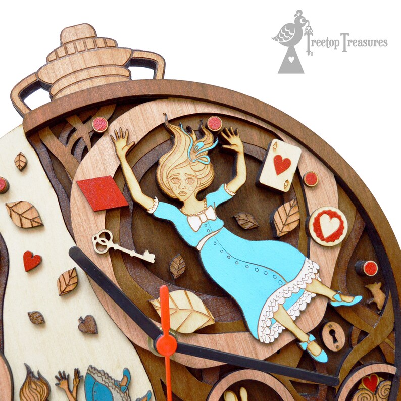K&ouml;nnte beinhalten: Holzuhr mit einem skurrilen Alice im Wunderland-Thema. Das Zifferblatt zeigt Alice im Fall, umgeben von Spielkarten, Schl&uuml;sseln und Bl&auml;ttern. Die Zeiger sind schwarz mit einem roten Sekundenzeiger. Die Uhr ist aus geschichtetem Holz gefertigt.
