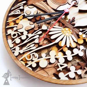 May include: A wooden clock with a red and black hand, featuring a laser-cut design of flowers, mushrooms, and leaves. The clock face is made of wood and has a natural wood finish. The clock is surrounded by a wooden frame.