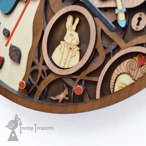 K&ouml;nnte beinhalten: Eine Holz-Uhr mit dem Thema Alice im Wunderland. Die Uhr zeigt ein wei&szlig;es Kaninchen in einem Rahmen, rote Herz-Akzente und ein rennendes Kaninchen. Die Uhrzeiger sind schwarz und das Zifferblatt ist hellbraun.