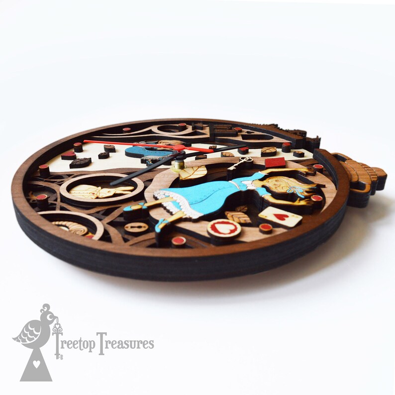 K&ouml;nnte beinhalten: Eine mehrschichtige Holzuhr mit dem Thema Alice im Wunderland. Die Uhr hat einen dunkelbraunen Rahmen und einen hellbraunen und wei&szlig;en Innenraum. Das Design umfasst Alice in einem blauen Kleid, Spielkarten und ein wei&szlig;es Kaninchen. Die Zeiger sind schwarz und rot.