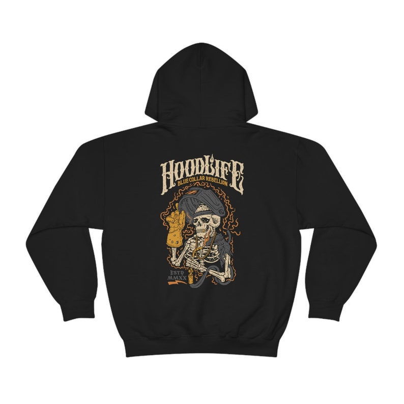 Pode incluir: Camisola de moletom com capuz preta com um gr&aacute;fico de um esqueleto usando uma m&aacute;scara de solda e segurando um ma&ccedil;arico de solda. O texto "HOODLIFE BLUE COLLAR REBELLION ESTD.MMXX" est&aacute; impresso na camisola.