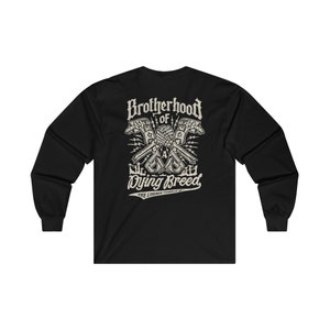 Op de afbeelding: Zwart langarm T-shirt met een grafische print van twee skeletachtige handen die een moersleutel en een hamer vasthouden, met de tekst "Brotherhood of a Dying Breed" en "The Lineman Company" eronder.