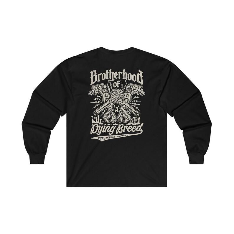 Op de afbeelding: Zwart langarm T-shirt met een grafische print van twee skeletachtige handen die een moersleutel en een hamer vasthouden, met de tekst "Brotherhood of a Dying Breed" en "The Lineman Company" eronder.