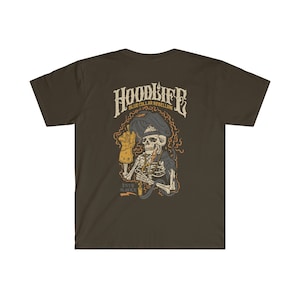 Pode incluir: Uma camiseta marrom com um gr&aacute;fico de um esqueleto usando uma m&aacute;scara de solda e segurando um ma&ccedil;arico de solda. O gr&aacute;fico tamb&eacute;m inclui o texto "HOODLIFE BLUE COLLAR REBELLION ESTD. MMXX".